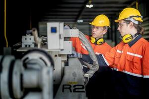 male engineer workers maintenance automatic robotic arm machine in a factory. worker checking and repairing automatic robot hand machine. technician worker check for repair factory machine. photo