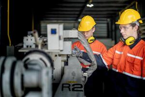 male engineer workers maintenance automatic robotic arm machine in a factory. worker checking and repairing automatic robot hand machine. technician worker check for repair factory machine. photo