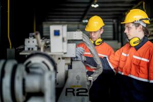 male engineer workers maintenance automatic robotic arm machine in a factory. worker checking and repairing automatic robot hand machine. technician worker check for repair factory machine. photo