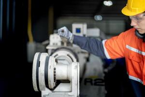 masculino ingeniero trabajadores mantenimiento automático robótico brazo máquina en un fábrica. trabajador comprobación y reparando automático robot mano máquina. técnico trabajador cheque para reparar fábrica máquina. foto