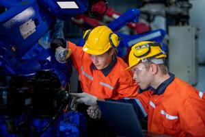 male engineer workers maintenance automatic robotic arm machine in a factory. worker checking and repairing automatic robot hand machine. technician worker check for repair factory machine. photo