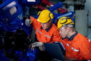 male engineer workers maintenance automatic robotic arm machine in a factory. worker checking and repairing automatic robot hand machine. technician worker check for repair factory machine. photo