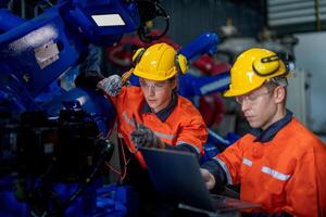 male engineer workers maintenance automatic robotic arm machine in a factory. worker checking and repairing automatic robot hand machine. technician worker check for repair factory machine. photo