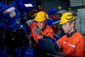 male engineer workers maintenance automatic robotic arm machine in a factory. worker checking and repairing automatic robot hand machine. technician worker check for repair factory machine. photo