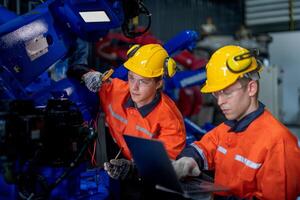 male engineer workers maintenance automatic robotic arm machine in a factory. worker checking and repairing automatic robot hand machine. technician worker check for repair factory machine. photo