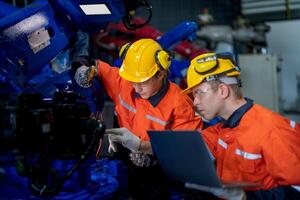 male engineer workers maintenance automatic robotic arm machine in a factory. worker checking and repairing automatic robot hand machine. technician worker check for repair factory machine. photo