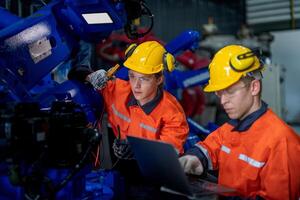 male engineer workers maintenance automatic robotic arm machine in a factory. worker checking and repairing automatic robot hand machine. technician worker check for repair factory machine. photo