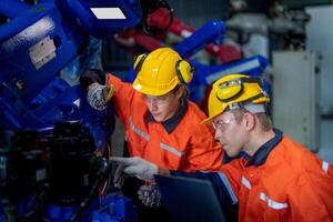 male engineer workers maintenance automatic robotic arm machine in a factory. worker checking and repairing automatic robot hand machine. technician worker check for repair factory machine. photo