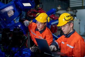 male engineer workers maintenance automatic robotic arm machine in a factory. worker checking and repairing automatic robot hand machine. technician worker check for repair factory machine. photo