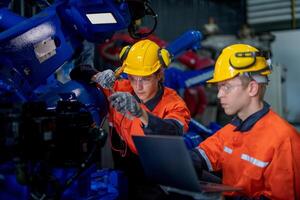 fábrica ingenieros inspeccionando en máquina con inteligente tableta. trabajador trabajos a pesado máquina robot brazo. el soldadura máquina con un remoto sistema en un industrial fábrica. artificial inteligencia concepto. foto