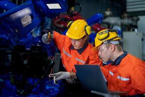 fábrica ingenieros inspeccionando en máquina con inteligente tableta. trabajador trabajos a pesado máquina robot brazo. el soldadura máquina con un remoto sistema en un industrial fábrica. artificial inteligencia concepto. foto