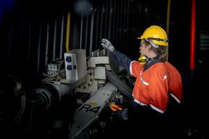 Engineer man checking the status of machine and used wrench to screw some part of equipment at CNC factory. Worker wearing safety glasses and helmet. Maintenance and repairing concept. photo