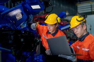 male engineer workers maintenance automatic robotic arm machine in a factory. worker checking and repairing automatic robot hand machine. technician worker check for repair factory machine. photo