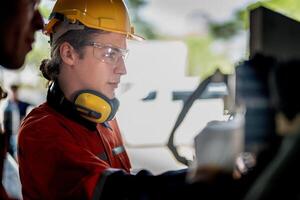 Engineer man checking the status of machine and used wrench to screw some part of equipment at CNC factory. Worker wearing safety glasses and helmet. Maintenance and repairing concept. photo