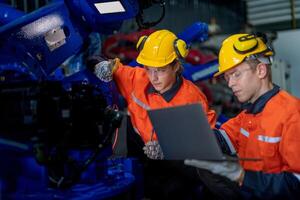 male engineer workers maintenance automatic robotic arm machine in a factory. worker checking and repairing automatic robot hand machine. technician worker check for repair factory machine. photo