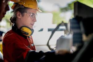 Engineer man checking the status of machine and used wrench to screw some part of equipment at CNC factory. Worker wearing safety glasses and helmet. Maintenance and repairing concept. photo