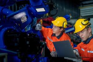 male engineer workers maintenance automatic robotic arm machine in a factory. worker checking and repairing automatic robot hand machine. technician worker check for repair factory machine. photo