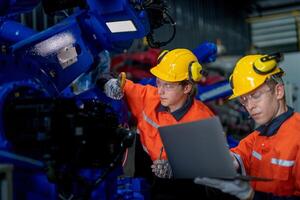 male engineer workers maintenance automatic robotic arm machine in a factory. worker checking and repairing automatic robot hand machine. technician worker check for repair factory machine. photo