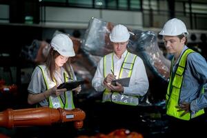 Sales manager and factory owner in suits negotiating selling robots used in the factory. Business engineers meeting and checking new machine robot. Workers walking at warehouse welding machine. photo