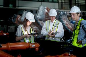 Sales manager and factory owner in suits negotiating selling robots used in the factory. Business engineers meeting and checking new machine robot. Workers walking at warehouse welding machine. photo