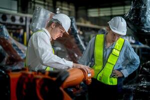 negocio ingenieros reunión y comprobación nuevo máquina robot. trabajadores caminando a almacén industria soldadura máquina. negocio negociación conceptos y tecnología. mujer utilizando inteligente tableta a presente hombre. foto