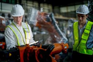 Business engineers meeting and checking new machine robot. Workers walking at warehouse industry welding machine. business negotiation concepts and technology. women Using smart Tablet to present man. photo