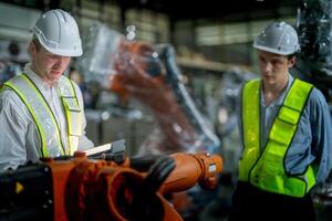 ventas gerente y fábrica propietario en trajes negociando de venta robots usado en el fábrica. negocio ingenieros reunión y comprobación nuevo máquina robot. trabajadores caminando a almacén soldadura máquina. foto