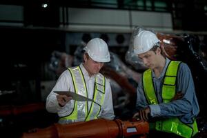 ventas gerente y fábrica propietario en trajes negociando de venta robots usado en el fábrica. negocio ingenieros reunión y comprobación nuevo máquina robot. trabajadores caminando a almacén soldadura máquina. foto