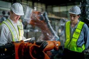 Sales manager and factory owner in suits negotiating selling robots used in the factory. Business engineers meeting and checking new machine robot. Workers walking at warehouse welding machine. photo