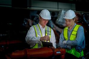 Business engineers meeting and checking new machine robot. Workers walking at warehouse industry welding machine. business negotiation concepts and technology. women Using smart Tablet to present man. photo