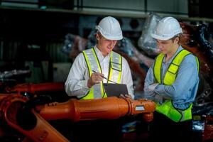 Sales manager and factory owner in suits negotiating selling robots used in the factory. Business engineers meeting and checking new machine robot. Workers walking at warehouse welding machine. photo