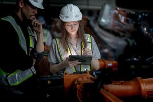 negocio ingenieros reunión y comprobación nuevo máquina robot. trabajadores caminando a almacén industria soldadura máquina. negocio negociación conceptos y tecnología. mujer utilizando inteligente tableta a presente hombre. foto