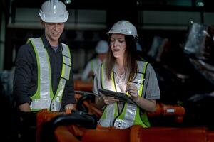 Sales manager and factory owner in suits negotiating selling robots used in the factory. Business engineers meeting and checking new machine robot. Workers walking at warehouse welding machine. photo