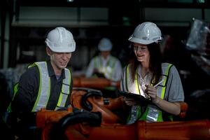 ventas gerente y fábrica propietario en trajes negociando de venta robots usado en el fábrica. negocio ingenieros reunión y comprobación nuevo máquina robot. trabajadores caminando a almacén soldadura máquina. foto