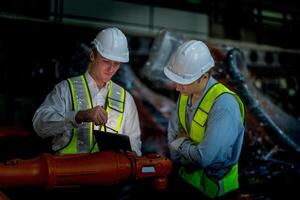 negocio ingenieros reunión y comprobación nuevo máquina robot. trabajadores caminando a almacén industria soldadura máquina. negocio negociación conceptos y tecnología. mujer utilizando inteligente tableta a presente hombre. foto