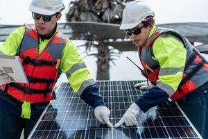 engineer men inspect modules of photovoltaic cell panels. Industrial Renewable energy of green power. workers prepare materials before construction on site with the stack of panels at background. photo