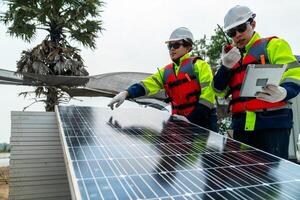 engineer men inspect modules of photovoltaic cell panels. Industrial Renewable energy of green power. workers prepare materials before construction on site with the stack of panels at background. photo