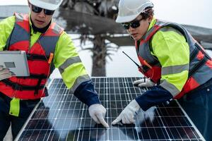 ingeniero hombres inspeccionar módulos de fotovoltaica célula paneles industrial renovable energía de verde fuerza. trabajadores preparar materiales antes de construcción en sitio con el apilar de paneles a antecedentes. foto