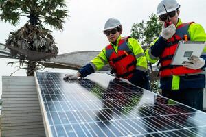 engineer men inspect modules of photovoltaic cell panels. Industrial Renewable energy of green power. workers prepare materials before construction on site with the stack of panels at background. photo