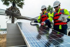 engineer men inspect modules of photovoltaic cell panels. Industrial Renewable energy of green power. workers prepare materials before construction on site with the stack of panels at background. photo