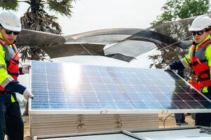 engineer men inspect modules of photovoltaic cell panels. Industrial Renewable energy of green power. workers prepare materials before construction on site with the stack of panels at background. photo