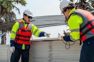 engineer men inspect modules of photovoltaic cell panels. Industrial Renewable energy of green power. workers prepare materials before construction on site with the stack of panels at background. photo