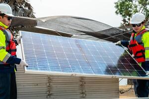 engineer men inspect modules of photovoltaic cell panels. Industrial Renewable energy of green power. workers prepare materials before construction on site with the stack of panels at background. photo