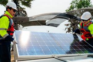 engineer men inspect modules of photovoltaic cell panels. Industrial Renewable energy of green power. workers prepare materials before construction on site with the stack of panels at background. photo