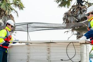 ingeniero hombres inspeccionar módulos de fotovoltaica célula paneles industrial renovable energía de verde fuerza. trabajadores preparar materiales antes de construcción en sitio con el apilar de paneles a antecedentes. foto