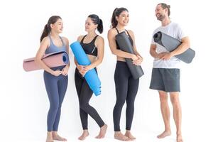 Group of happy sporty women and guy wearing body stylish sportswear holding personal carpets leaned on a white background. waiting for yoga class or body weight class. healthy lifestyle and wellness photo