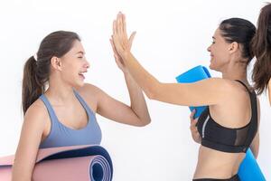 Group of happy sporty women talking with body stylish sportswear holding personal carpets leaned on a white background. waiting for yoga class or body weight class. healthy lifestyle and wellness photo