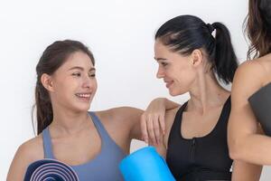 Group of happy sporty women and guy wearing body stylish sportswear holding personal carpets leaned on a white background. waiting for yoga class or body weight class. healthy lifestyle and wellness photo