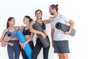 Group of happy sporty women and guy wearing body stylish sportswear holding personal carpets leaned on a white background. waiting for yoga class or body weight class. healthy lifestyle and wellness photo