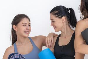 Group of happy sporty women and guy wearing body stylish sportswear holding personal carpets leaned on a white background. waiting for yoga class or body weight class. healthy lifestyle and wellness photo